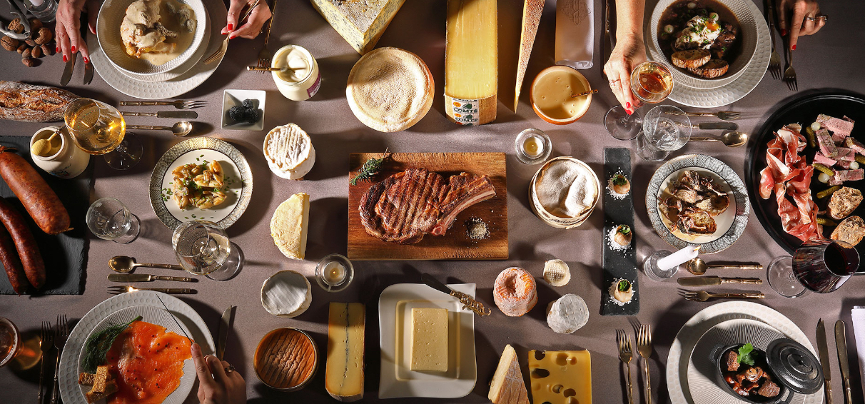 Photographie d'une table vue de haut avec plusieurs produits régionaux disposés comme pour un repas en famille.